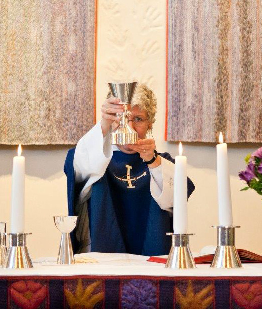 Picture of Ninna in her priest robe at an altar.